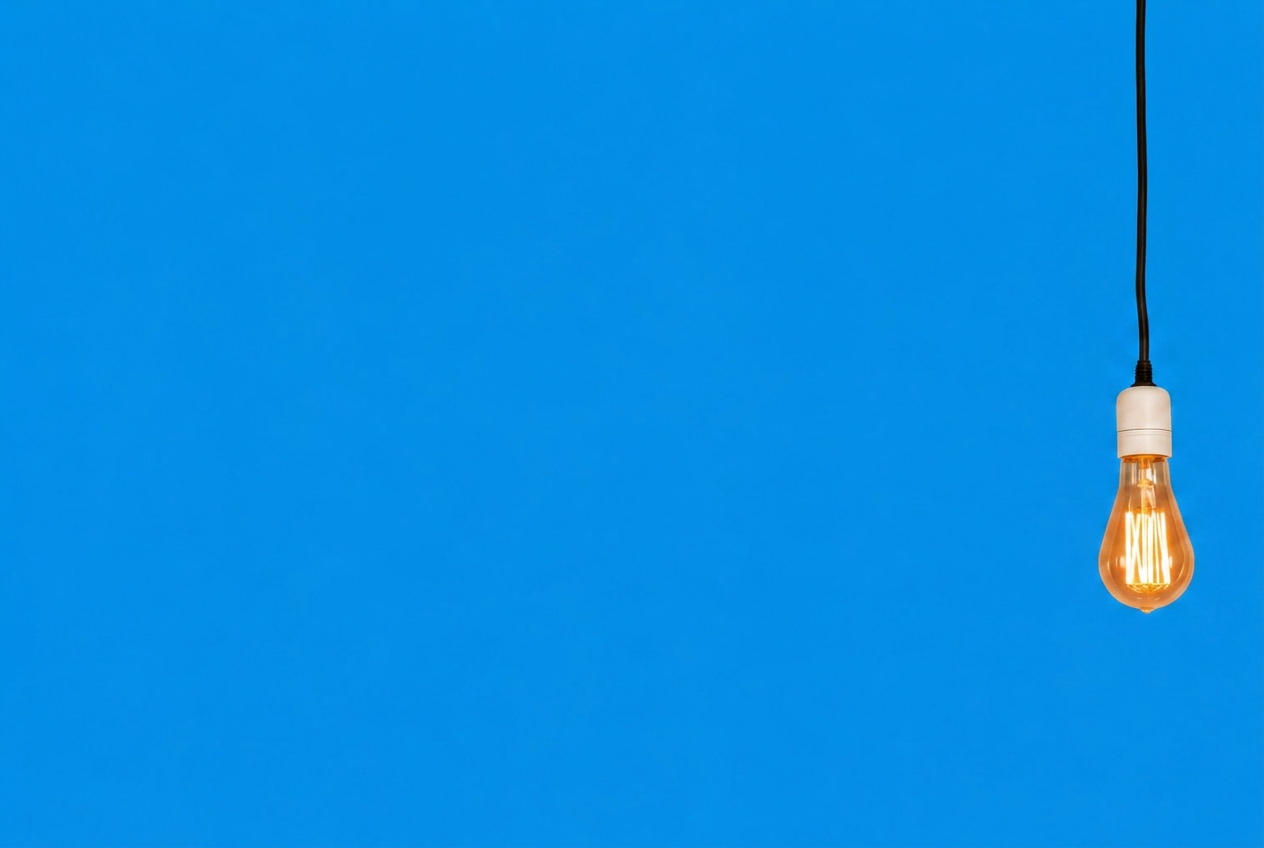 A single warm filament bulb glowing against a soft blue backdrop